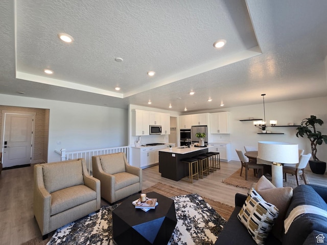 4286 W 1600 S Unit 301, Ogden, UT 84404 - living area featuring a textured ceiling, a tray ceiling, light wood-type flooring, recessed lighting, and a chandelier