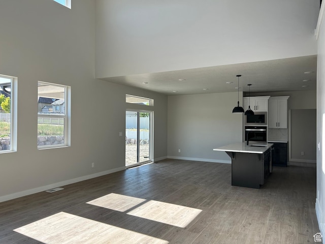 1597 N Cozy Ln Unit 14, Saratoga Springs, UT 84045 - unfurnished living room with wood finished floors, baseboards, a towering ceiling, and recessed lighting