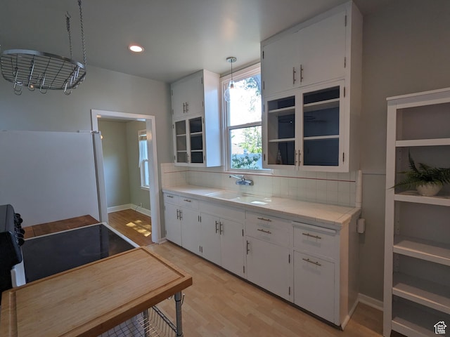 1130 S 1300 E, Salt Lake City, UT 84105 - kitchen with freestanding refrigerator, backsplash, light wood-style floors, white cabinetry, and recessed lighting