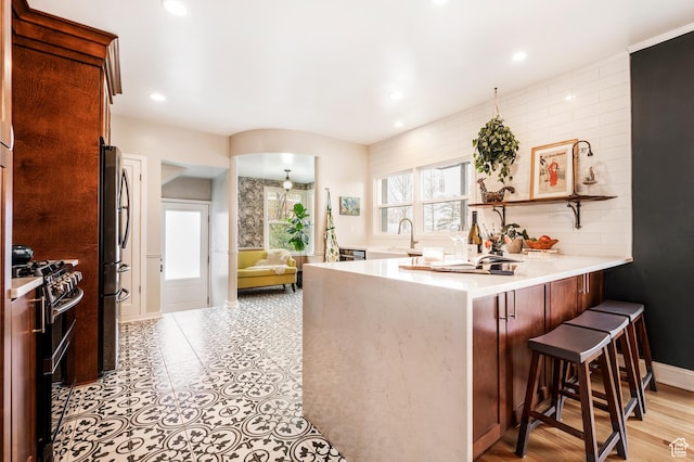 1130 S 1300 E, Salt Lake City, UT 84105 - kitchen featuring appliances with stainless steel finishes, a peninsula, light countertops, a breakfast bar area, and recessed lighting