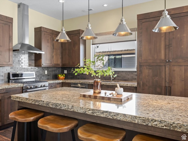 5943 E Big Horn Pkwy, Eden, UT 84310 - kitchen with wall chimney exhaust hood, gas stove, a kitchen breakfast bar, light stone countertops, and backsplash