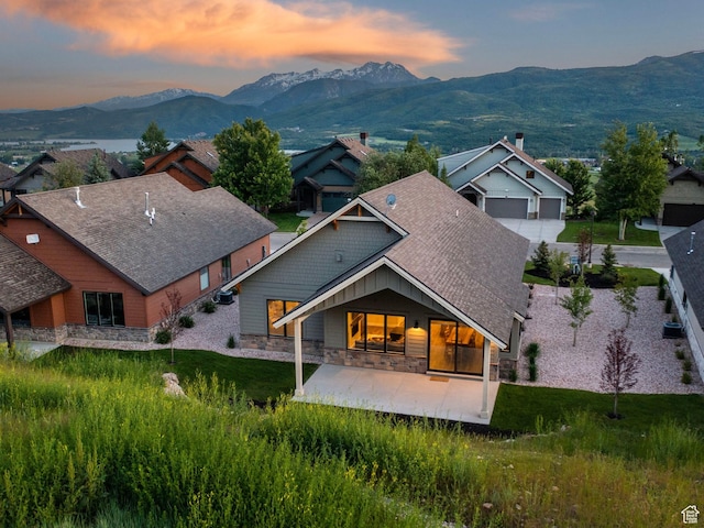 5943 E Big Horn Pkwy, Eden, UT 84310 - back of property featuring stone siding, a mountain view, a patio, and a shingled roof