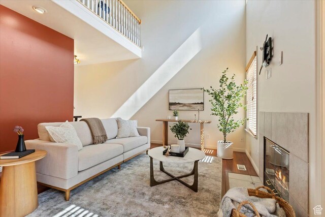 7825 S Spruce Tree Ln, Sandy, UT 84094 - living room featuring wood finished floors, a fireplace with flush hearth, baseboards, and a high ceiling