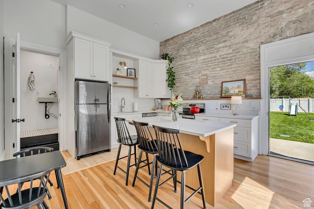 119 E 400 S, Provo, UT 84606 - kitchen featuring stainless steel appliances, open shelves, brick wall, light wood-style flooring, and light countertops