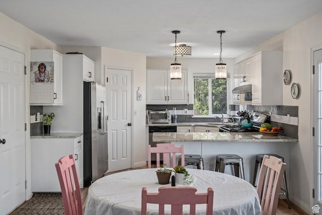 116 S Canyon View Dr, Elk Ridge, UT 84651 - kitchen with stainless steel appliances, under cabinet range hood, a peninsula, decorative backsplash, and hanging light fixtures