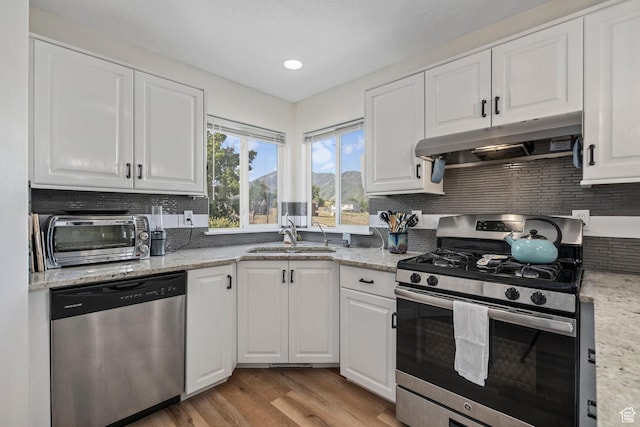 116 S Canyon View Dr, Elk Ridge, UT 84651 - kitchen with appliances with stainless steel finishes, under cabinet range hood, a sink, backsplash, and white cabinetry