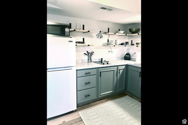 116 S Canyon View Dr, Elk Ridge, UT 84651 - kitchen with freestanding refrigerator, stainless steel microwave, open shelves, light wood-style floors, and black electric stovetop