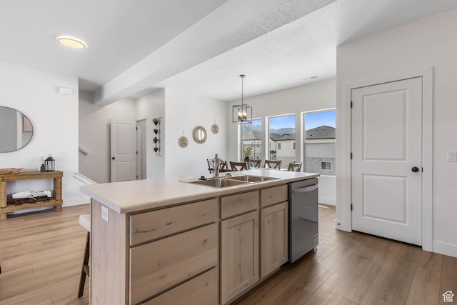 606 W Caroles Way, Tooele, UT 84074 - kitchen with stainless steel dishwasher, a sink, a kitchen island with sink, light wood-style floors, and light countertops