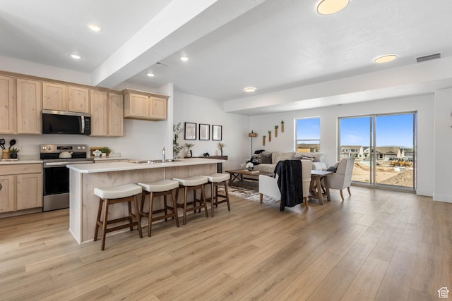 606 W Caroles Way, Tooele, UT 84074 - kitchen featuring stainless steel appliances, light brown cabinetry, a sink, a kitchen breakfast bar, and light countertops