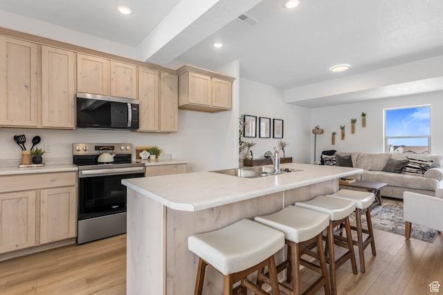 606 W Caroles Way, Tooele, UT 84074 - kitchen with stainless steel appliances, light brown cabinetry, a sink, open floor plan, and a breakfast bar