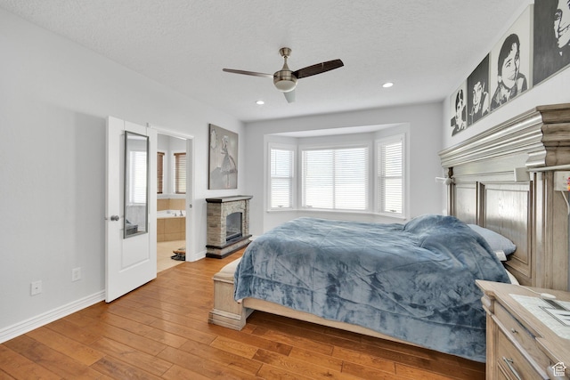 14789 S Briar Park Rd W, Herriman, UT 84096 - bedroom featuring wood-type flooring, baseboards, a fireplace with raised hearth, recessed lighting, and a ceiling fan