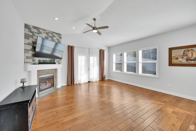 14789 S Briar Park Rd W, Herriman, UT 84096 - unfurnished living room featuring ceiling fan, light wood-style flooring, a large fireplace, vaulted ceiling, and baseboards