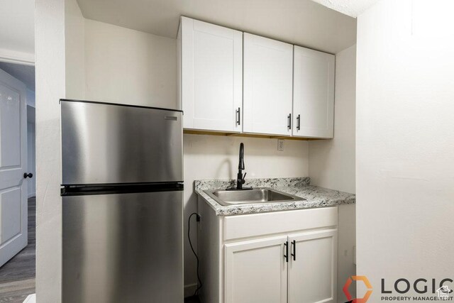 2743 Liberty Ave, Ogden, UT 84403 - kitchen with freestanding refrigerator, a sink, white cabinets, and wood finished floors