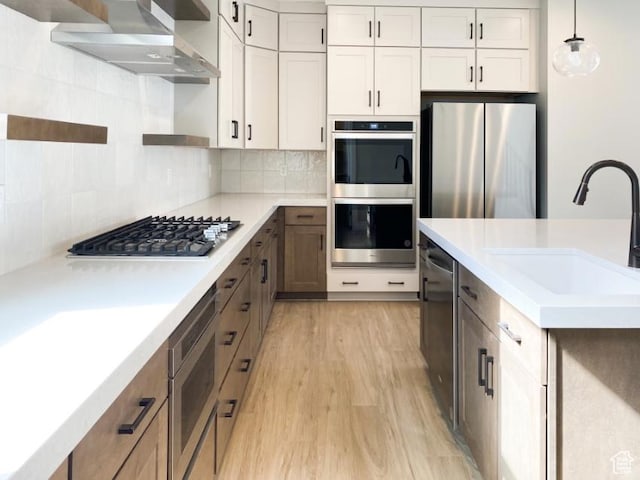 1594 W Canyon Rim N Unit 609, Lehi, UT 84043 - kitchen featuring appliances with stainless steel finishes, a sink, light wood-style floors, wall chimney exhaust hood, and light countertops