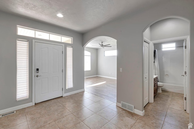2832 N Turnberry Ln, Lehi, UT 84043 - entryway featuring arched walkways, a textured ceiling, light tile patterned flooring, a ceiling fan, and baseboards