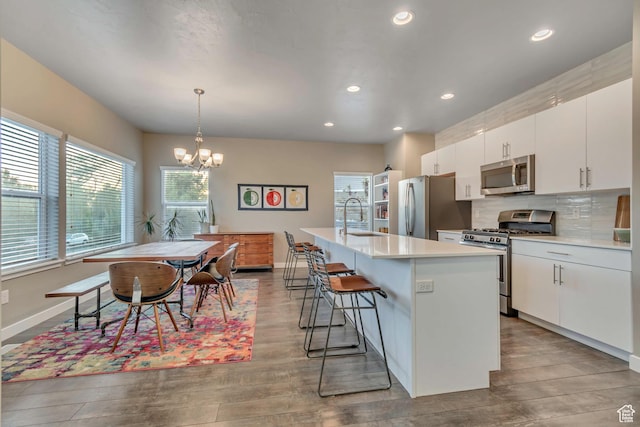 1791 W 60 S, Pleasant Grove, UT 84062 - kitchen featuring appliances with stainless steel finishes, a sink, light countertops, a breakfast bar area, and an island with sink