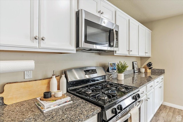 204 E 460 N, Vineyard, UT 84059 - kitchen featuring stainless steel appliances, white cabinets, light wood finished floors, dark stone counters, and baseboards