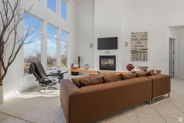 4554 W Birdie Way S, Jordan, UT 84009 - living room featuring a high ceiling, light tile patterned flooring, a glass covered fireplace, and baseboards
