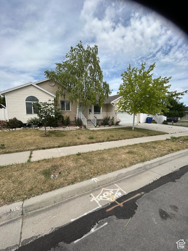 3086 S Fernbush Dr, Magna, UT 84044 - view of property hidden behind natural elements with concrete driveway, a garage, a front lawn, and covered porch