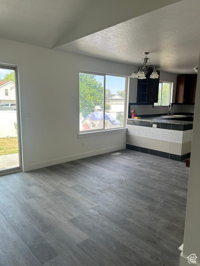 3086 S Fernbush Dr, Magna, UT 84044 - unfurnished living room featuring dark wood-style floors, a chandelier, baseboards, a sink, and a textured ceiling