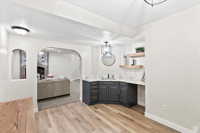 521 W Western Dr S, Kaysville, UT 84037 - bar area with a sink, a large fireplace, light wood-style floors, and arched walkways