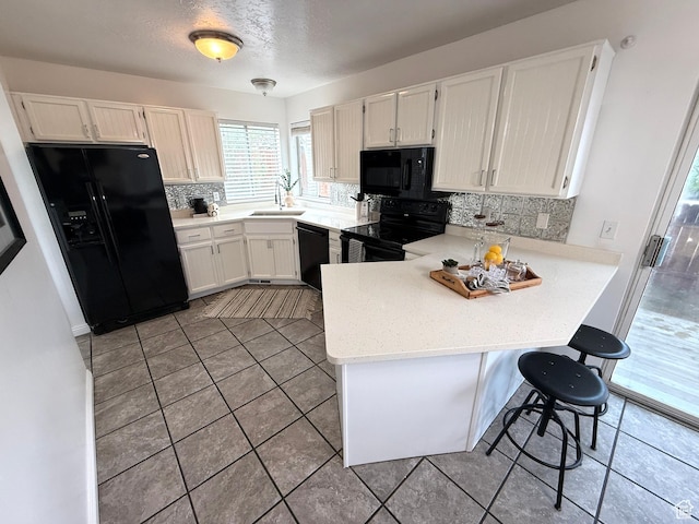 206 E Handcart Way, Sandy, UT 84070 - kitchen featuring black appliances, a peninsula, decorative backsplash, light tile patterned flooring, and light countertops