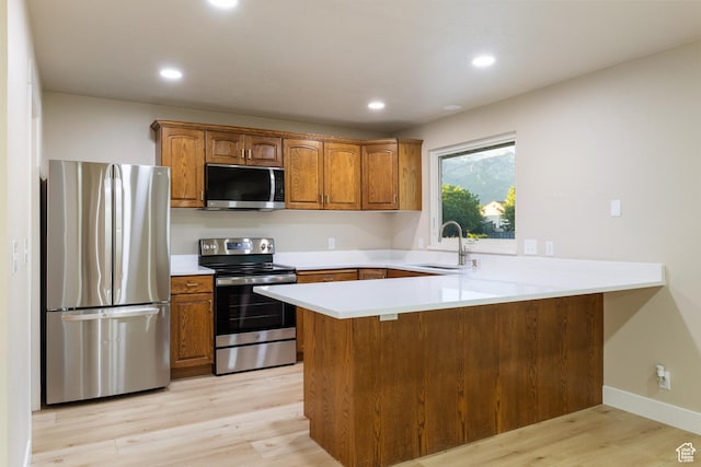 10861 N Panorama Dr, Highland, UT 84003 - kitchen with stainless steel appliances, a peninsula, brown cabinetry, light wood finished floors, and recessed lighting