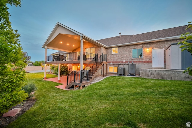 4234 W Swensen Farm Dr S, Riverton, UT 84096 - rear view of house featuring stairs, a wooden deck, brick siding, a lawn, and central AC unit