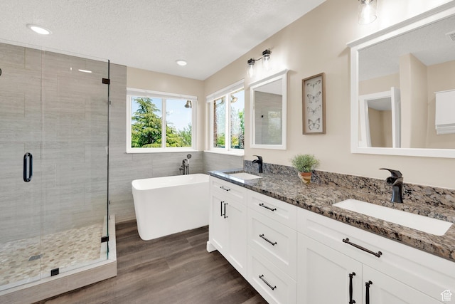 4234 W Swensen Farm Dr S, Riverton, UT 84096 - full bath featuring a shower stall, a textured ceiling, wood finished floors, double vanity, and a freestanding tub