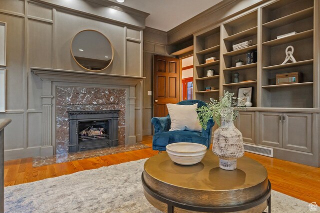 1358 E Tomahawk Dr N, Salt Lake City, UT 84103 - living area featuring light wood-type flooring, crown molding, a decorative wall, a fireplace, and built in features