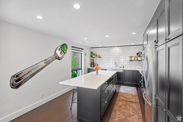 939 S Donner Way Unit 308, Salt Lake City, UT 84108 - kitchen with open shelves, freestanding refrigerator, a center island, backsplash, and a breakfast bar area
