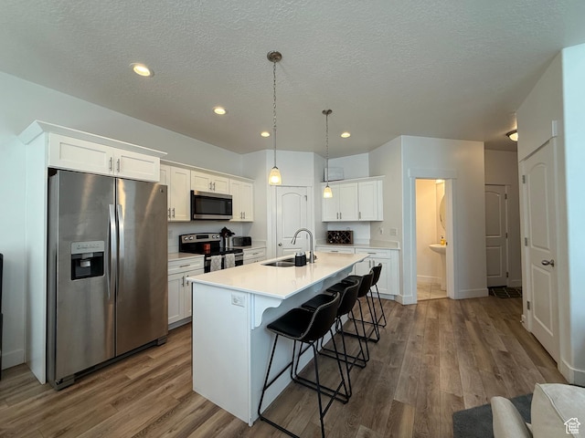 4323 W Burwell Ln, Herriman, UT 84096 - kitchen with stainless steel appliances, a sink, a breakfast bar, dark wood finished floors, and white cabinets