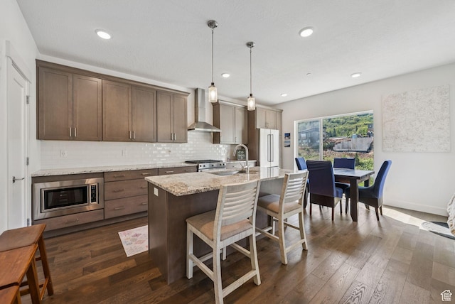 8210 N Toll Creek Ln, Park City, UT 84098 - kitchen featuring wall chimney range hood, appliances with stainless steel finishes, tasteful backsplash, a breakfast bar, and a sink
