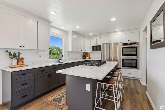 582 S Marialana Way E, North Salt Lake, UT 84054 - kitchen featuring gray cabinetry, appliances with stainless steel finishes, white cabinets, a kitchen breakfast bar, and a sink