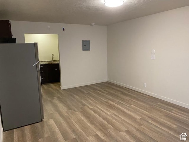 620 W Main St, Green River, UT 84525 - empty room featuring light wood-type flooring, a sink, electric panel, and baseboards