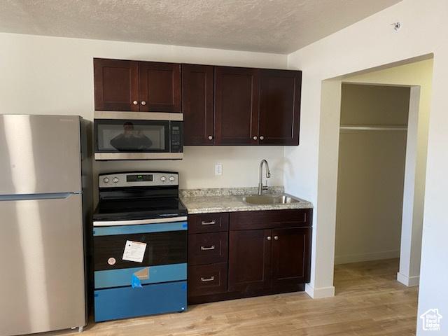 620 W Main St, Green River, UT 84525 - kitchen featuring stainless steel appliances, a sink, light wood finished floors, dark brown cabinets, and baseboards