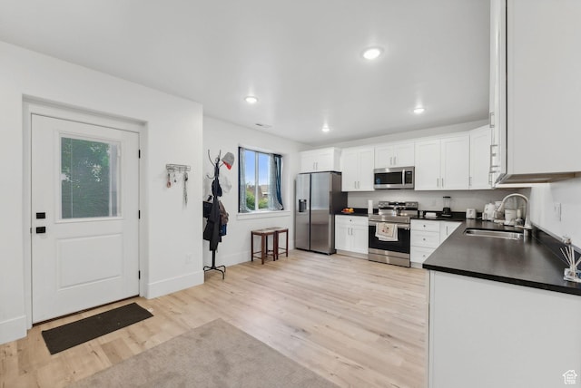 786 S 820 E, Pleasant Grove, UT 84062 - kitchen with appliances with stainless steel finishes, a sink, dark countertops, white cabinetry, and light wood finished floors