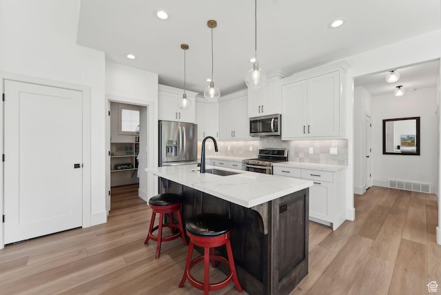 786 S 820 E, Pleasant Grove, UT 84062 - kitchen featuring stainless steel appliances, a sink, light wood-type flooring, tasteful backsplash, and a kitchen bar