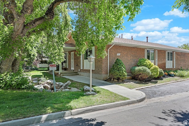 895 E 1015 S, Ogden, UT 84404 - view of property hidden behind natural elements featuring brick siding, a front yard, and roof with shingles