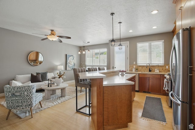 333 E Stanton Ave S, Salt Lake City, UT 84111 - kitchen with appliances with stainless steel finishes, light countertops, open floor plan, light wood finished floors, and brown cabinetry