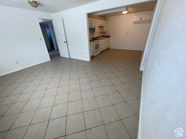 3780 S 7200 W, Magna, UT 84044 - unfurnished living room featuring a sink, light tile patterned floors, and baseboards