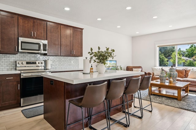 105 S 600 E, Provo, UT 84606 - kitchen featuring stainless steel appliances, a center island, backsplash, light countertops, and a kitchen breakfast bar