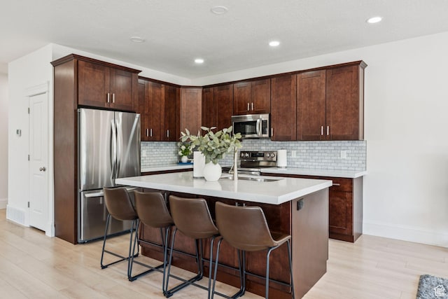 105 S 600 E, Provo, UT 84606 - kitchen featuring appliances with stainless steel finishes, light wood-style floors, light countertops, a breakfast bar, and recessed lighting