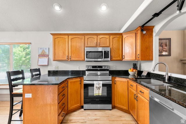 14008 S Emmeline Dr, Herriman, UT 84096 - kitchen with appliances with stainless steel finishes, a peninsula, a sink, light wood-style flooring, and a kitchen breakfast bar