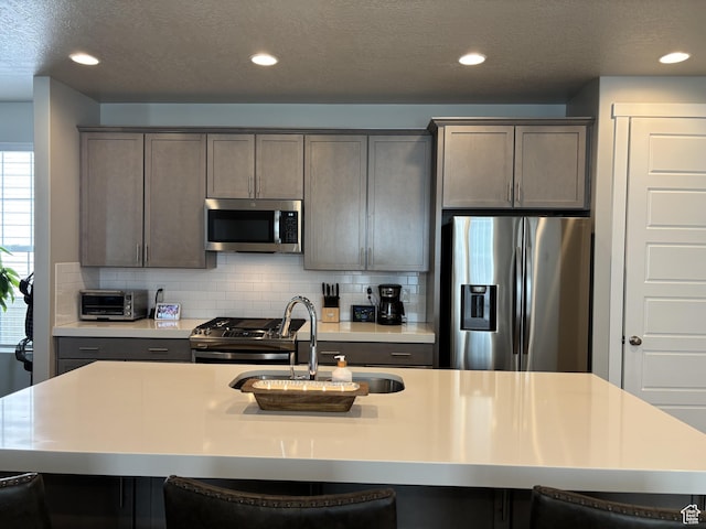 11603 S Outfitter Way S, Jordan, UT 84009 - kitchen featuring stainless steel appliances, a sink, a kitchen breakfast bar, decorative backsplash, and recessed lighting