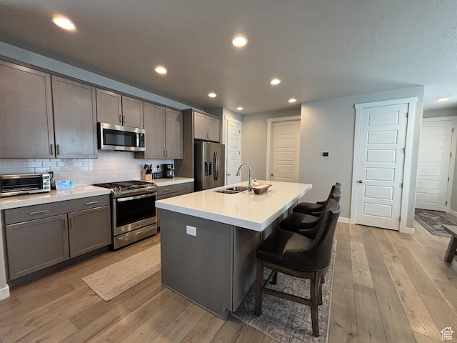 11603 S Outfitter Way S, Jordan, UT 84009 - kitchen featuring appliances with stainless steel finishes, a sink, light wood-style floors, recessed lighting, and backsplash
