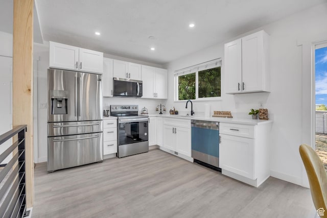 5494 W Townsend Way, West Valley City, UT 84118 - kitchen featuring appliances with stainless steel finishes, light wood finished floors, white cabinets, a sink, and recessed lighting