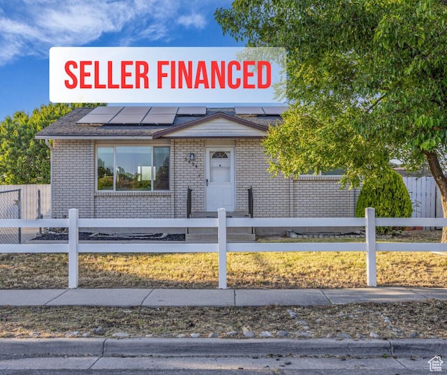 5494 W Townsend Way, West Valley City, UT 84118 - view of front of property with roof mounted solar panels, a fenced front yard, and brick siding