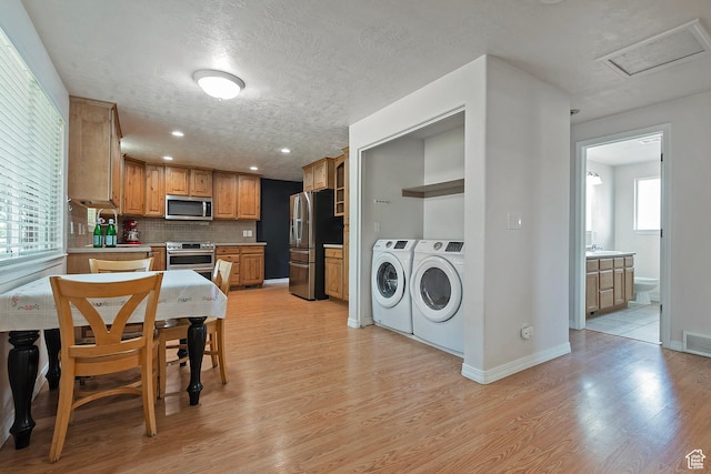 628 E Wyandotte Ave S, Sandy, UT 84070 - kitchen featuring appliances with stainless steel finishes, washer and dryer, light wood-type flooring, a textured ceiling, and backsplash