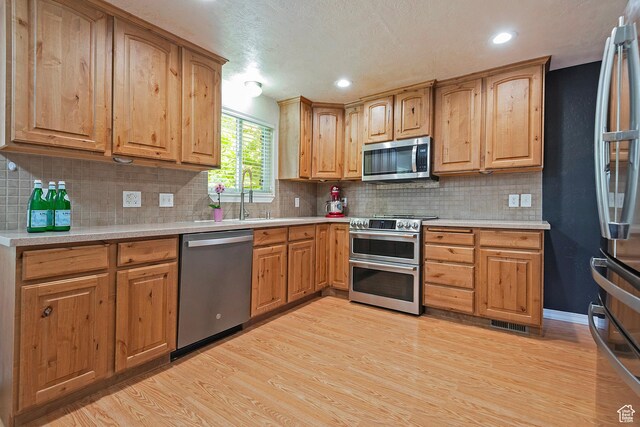 628 E Wyandotte Ave S, Sandy, UT 84070 - kitchen with appliances with stainless steel finishes, light wood-type flooring, light countertops, backsplash, and recessed lighting